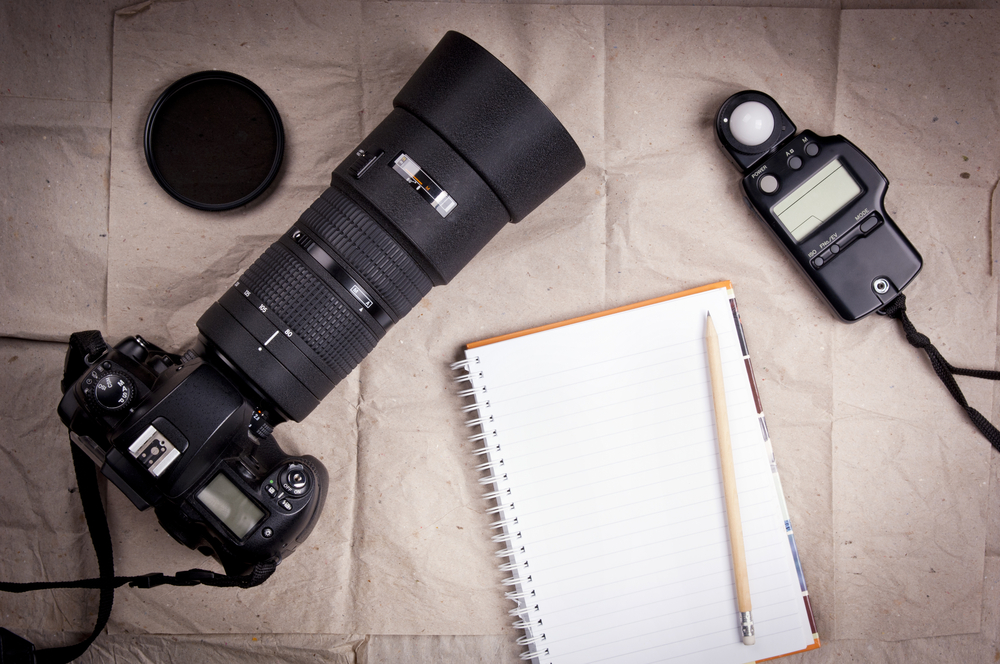 Photography equipment including a professional digital SLR camera and light meter with a blank notebook